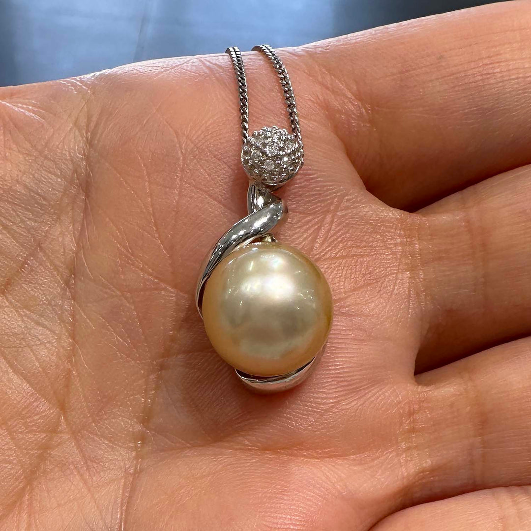 Close-up of a champagne-colored baroque South Sea pearl pendant in 14k white gold, featuring a unique spiral design with a diamond-studded top, total diamond weight 0.04 ct.