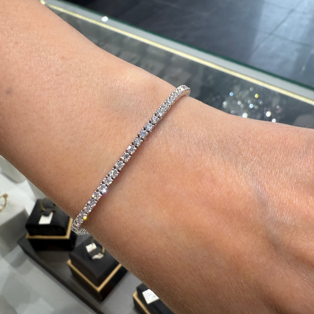 Close-up of a 14K white gold lab-grown diamond tennis bracelet with a four-prong, open-back basket-style setting, featuring 100 diamonds totaling 3.65 CT.