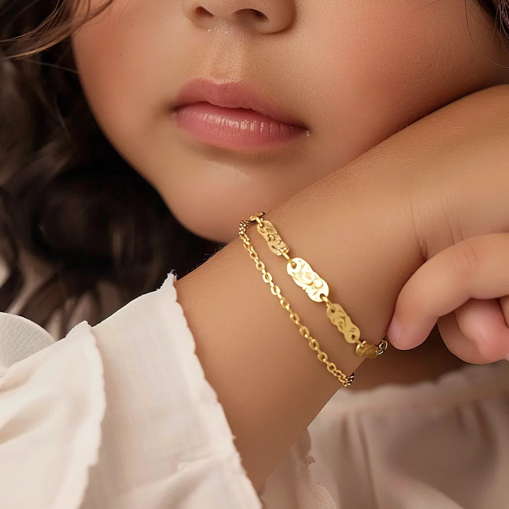 Close-up of a child wearing a delicate gold bracelet with intricate designs.