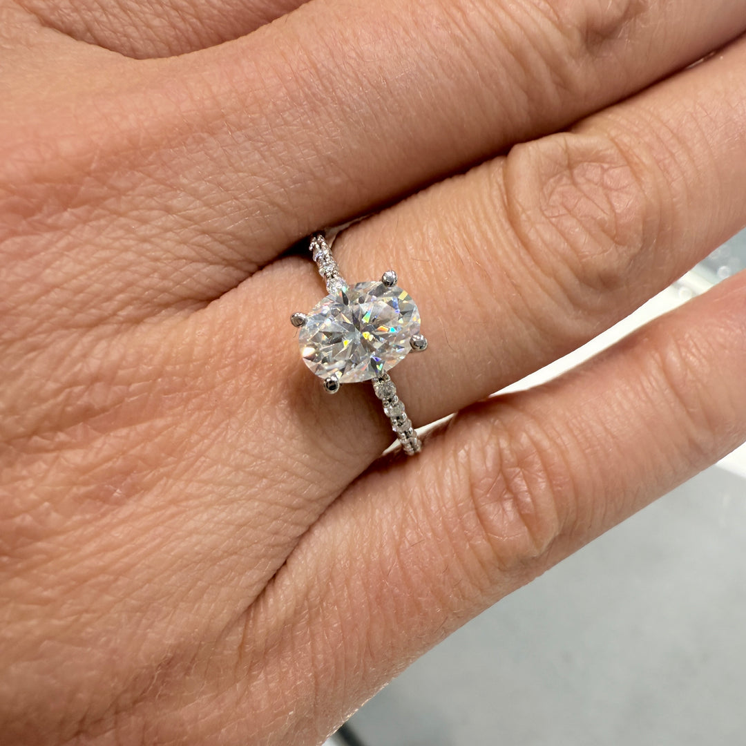 1 Ct oval moissanite engagement ring with pave band in 14K gold.