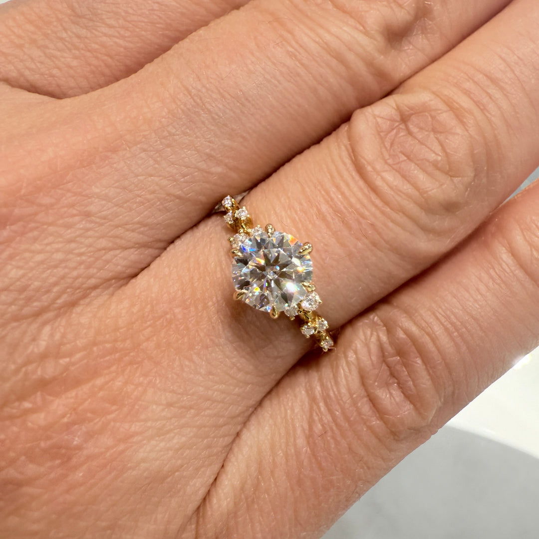 1 Ct round moissanite engagement ring with accent stones in 14K gold.