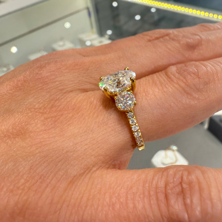 2 Ct oval moissanite three-stone engagement ring with side stones in 14K gold.