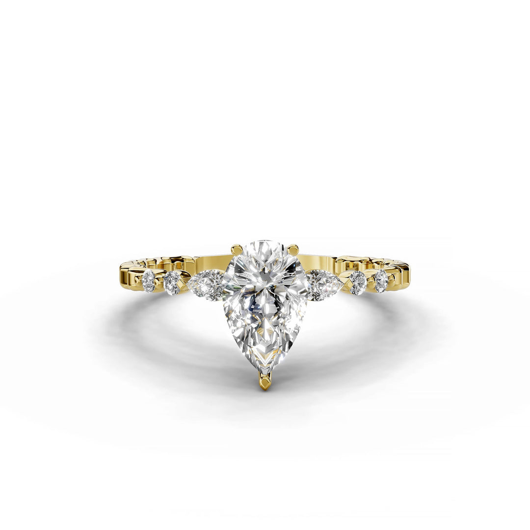 Pear-shaped diamond engagement ring, three-stone style, yellow gold band, geometric pattern.
