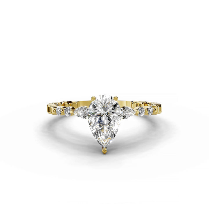Pear-shaped diamond engagement ring, three-stone style, yellow gold band, geometric pattern.