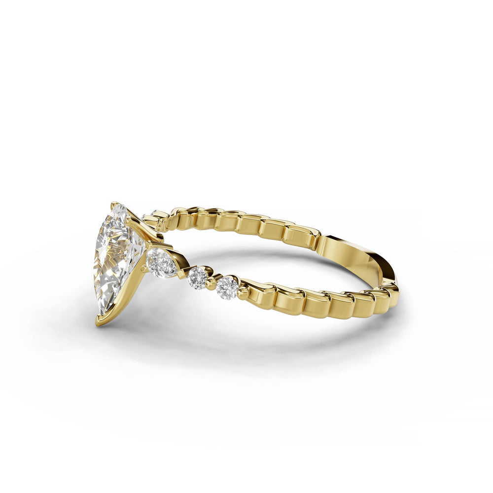 Pear-shaped diamond engagement ring, three-stone style, yellow gold band, geometric pattern.