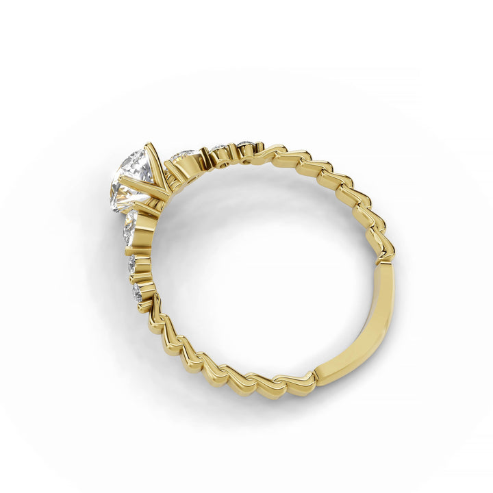 Pear-shaped diamond engagement ring, three-stone style, yellow gold band, geometric pattern.