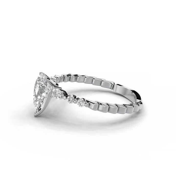 Pear-shaped diamond engagement ring, three-stone style, white gold band, geometric pattern.