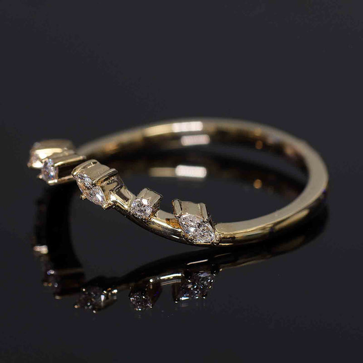 Curved wedding band with lab-grown round and marquise diamonds in shared prongs, open design.