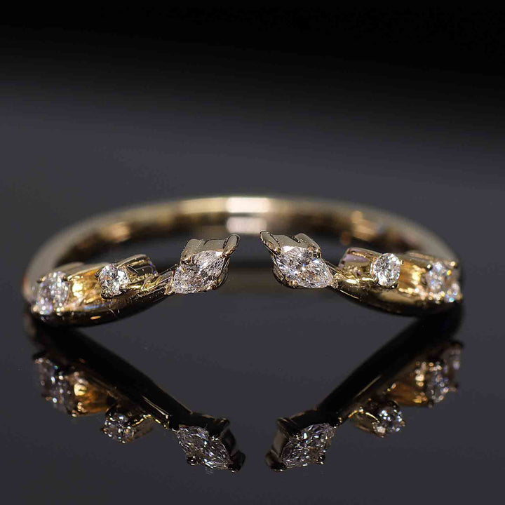 Curved wedding band with lab-grown round and marquise diamonds in shared prongs, open design.