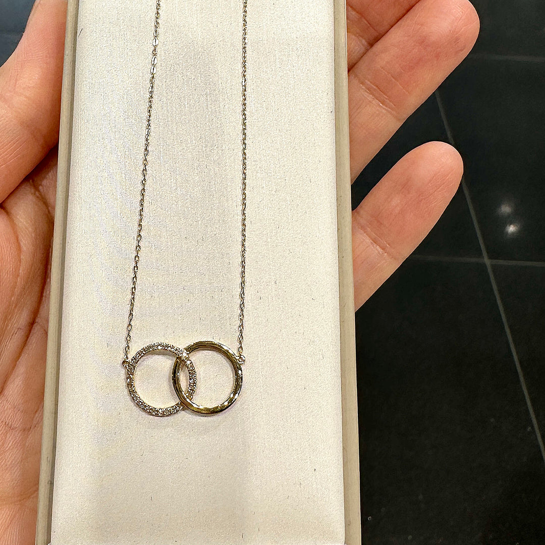 Close-up of a 14K yellow gold infinity necklace with interlocking circles and 0.08ct natural diamonds.
