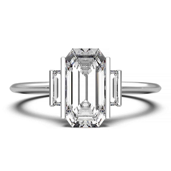 Three-stone engagement ring with emerald-cut diamond, baguette side stones, and modern bar prong setting.