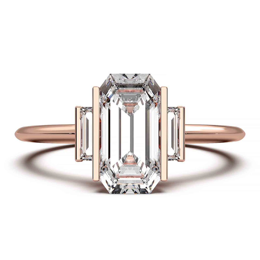 Three-stone engagement ring with emerald-cut diamond, baguette side stones, and modern bar prong setting.