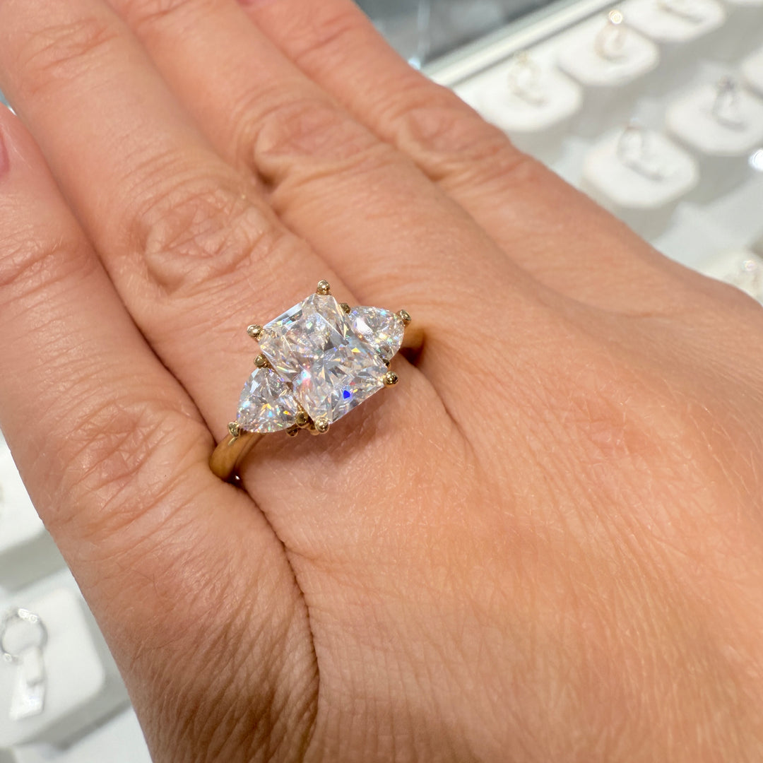 Radiant-cut moissanite ring with trillion side stones set in 14K yellow gold.