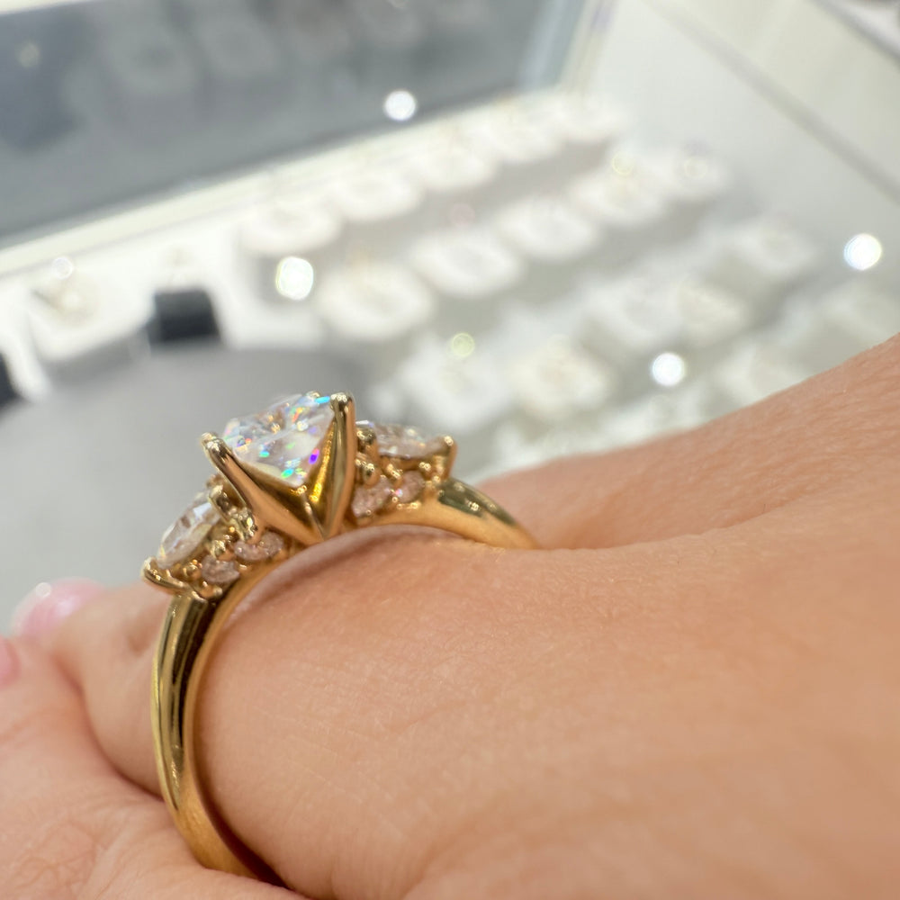 Radiant-cut moissanite ring with trillion side stones set in 14K yellow gold.