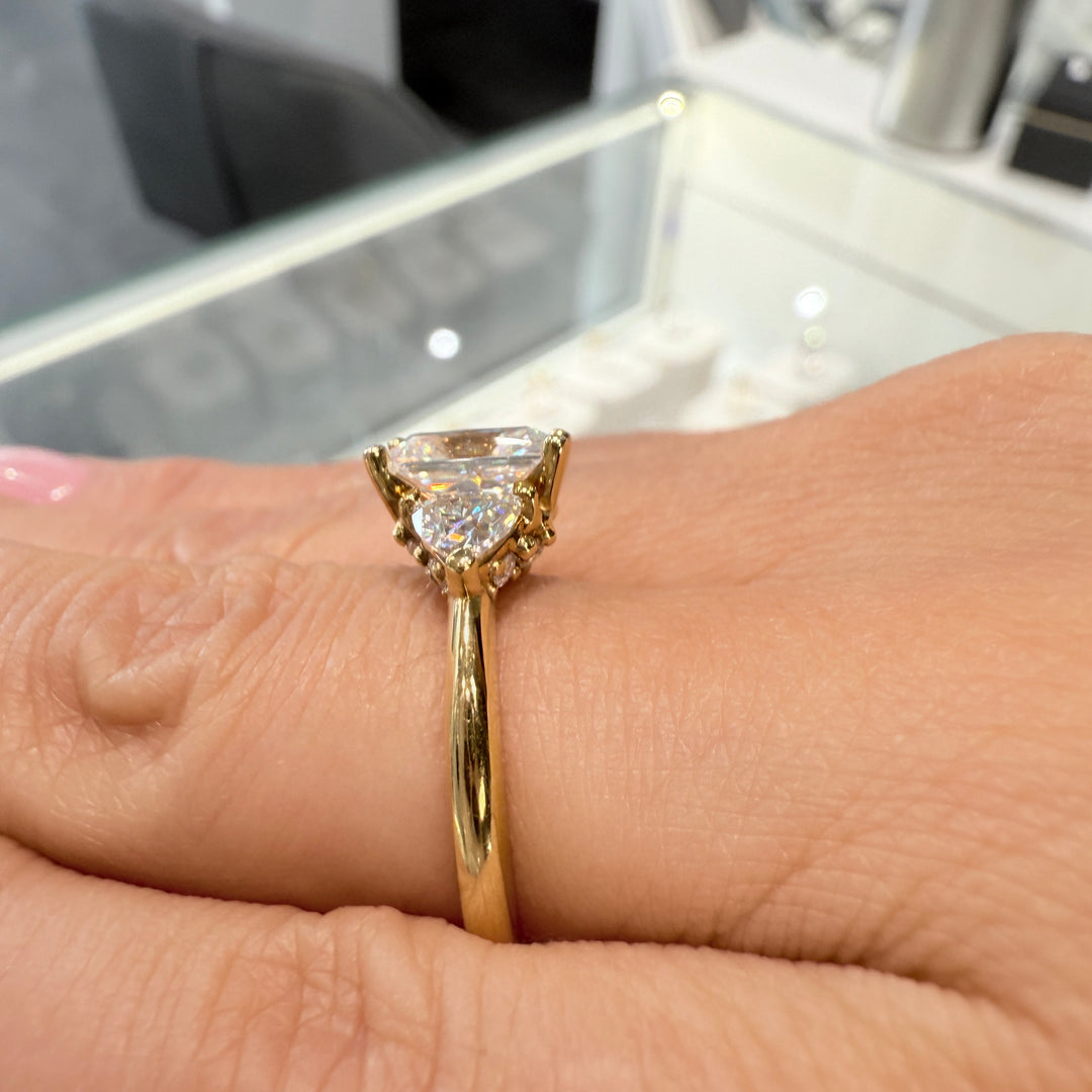 Radiant-cut moissanite ring with trillion side stones set in 14K yellow gold.