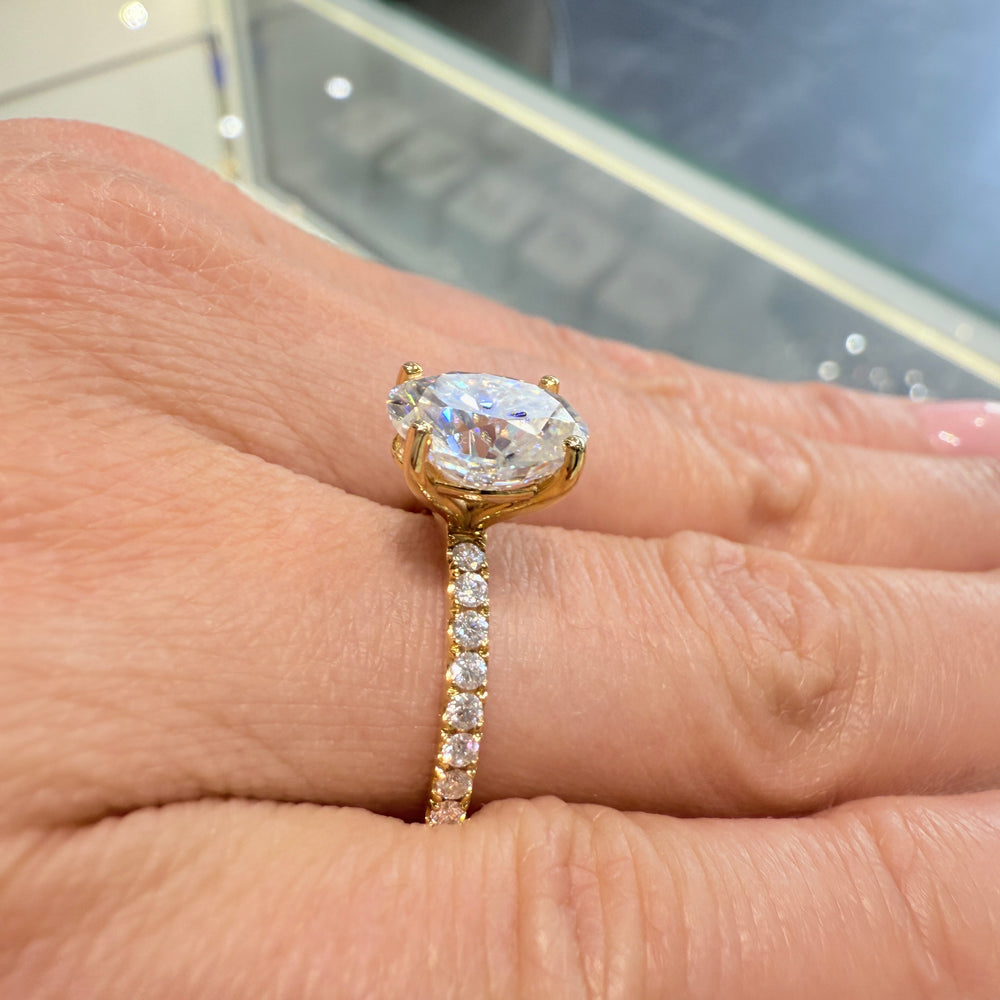2.5 Ct oval moissanite engagement ring with pave band in 14K gold.