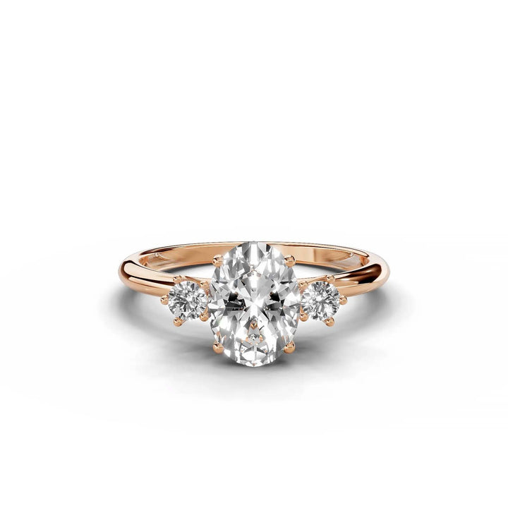 Oval diamond three-stone engagement ring in rose gold with round side stones.