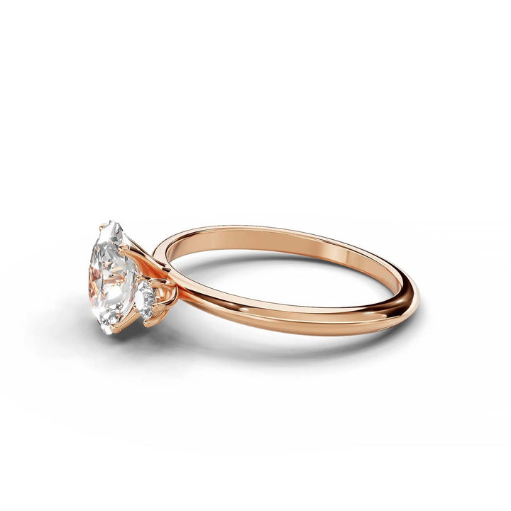 Oval diamond three-stone engagement ring in rose gold with round side stones.