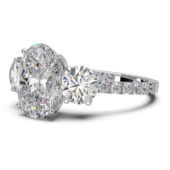 Three-stone engagement ring with 2-carat oval lab-grown diamond, round side stones, and pave band