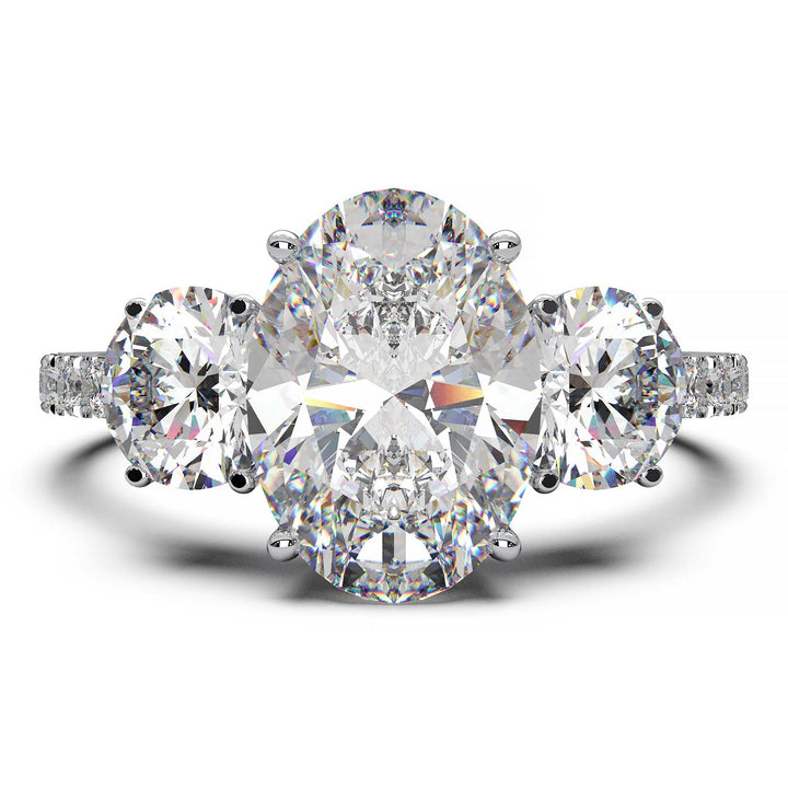 Three-stone engagement ring with 2-carat oval lab-grown diamond, round side stones, and pave band