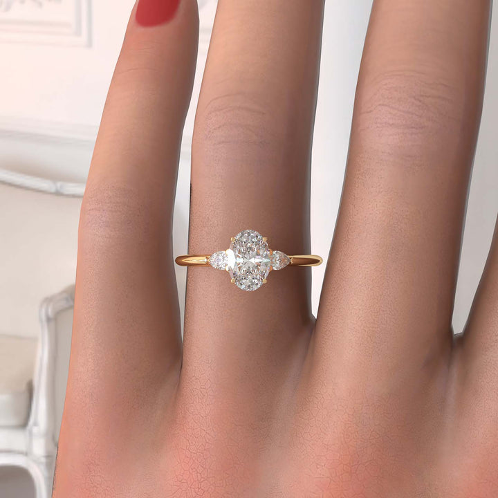 engagement ring featuring a 1 carat oval lab-grown diamond with pear-shaped side stones, held by unique cathedral-inspired prongs on a hand