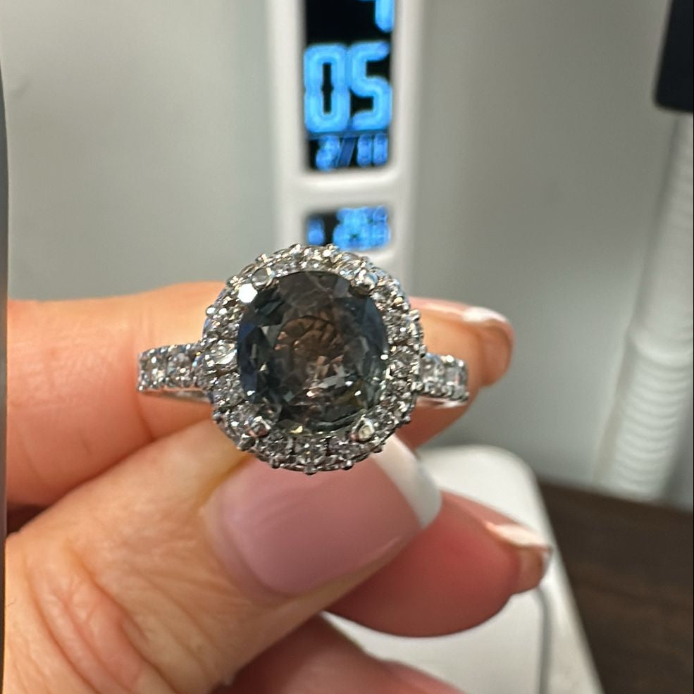 Round-cut color-changing sapphire ring with diamond halo in 14K gold.
