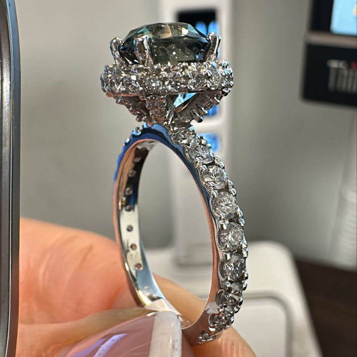 Round-cut color-changing sapphire ring with diamond halo in 14K gold.
