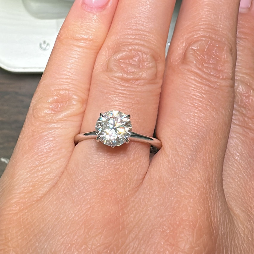 7.5mm round colorless moissanite solitaire ring in 14K gold.
