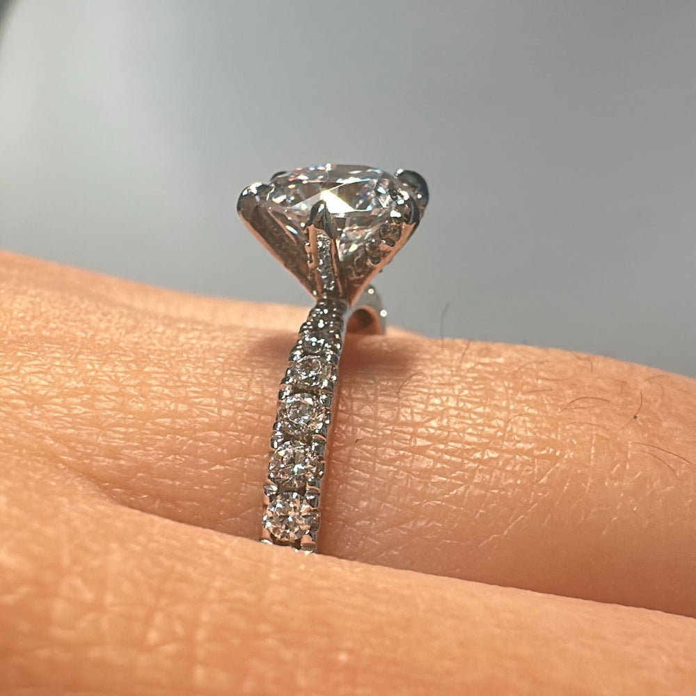 1 CT round moissanite engagement ring with small moissanite accents in 14K gold.