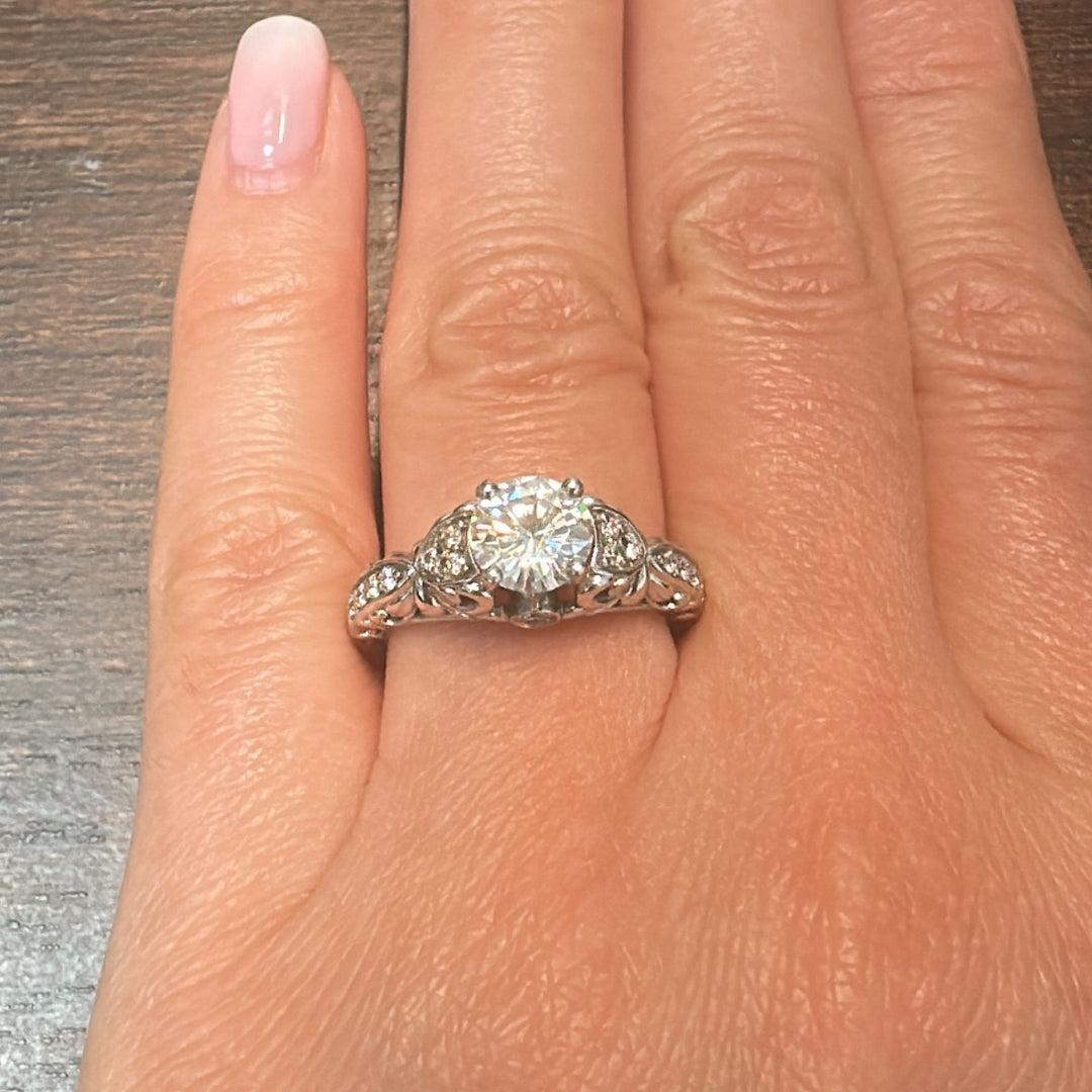 0.87 CT round moissanite vintage engagement ring in 14K white gold with small diamonds.