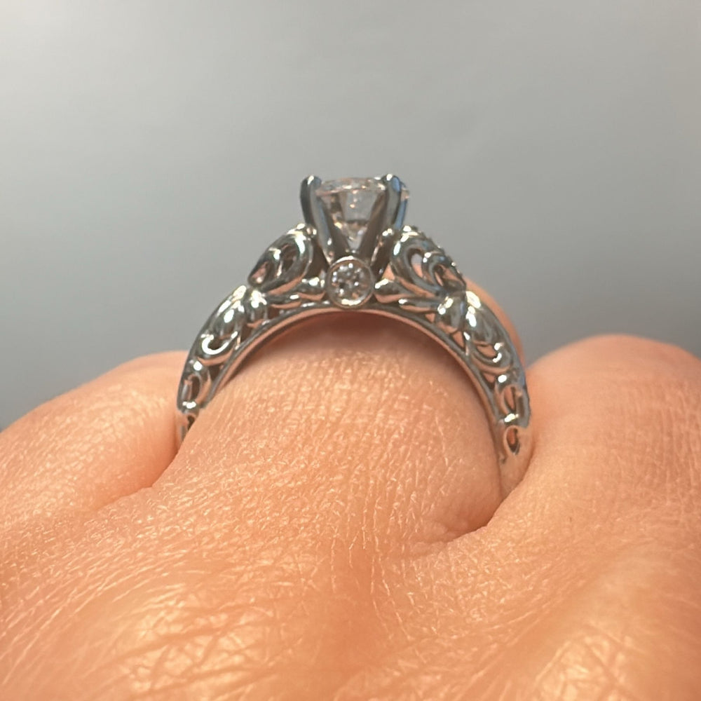 0.87 CT round moissanite vintage engagement ring in 14K white gold with small diamonds.