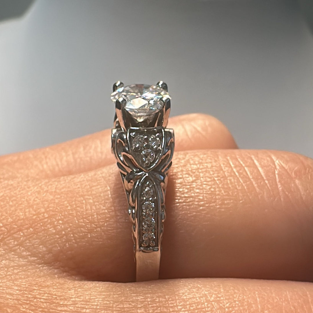 0.87 CT round moissanite vintage engagement ring in 14K white gold with small diamonds.