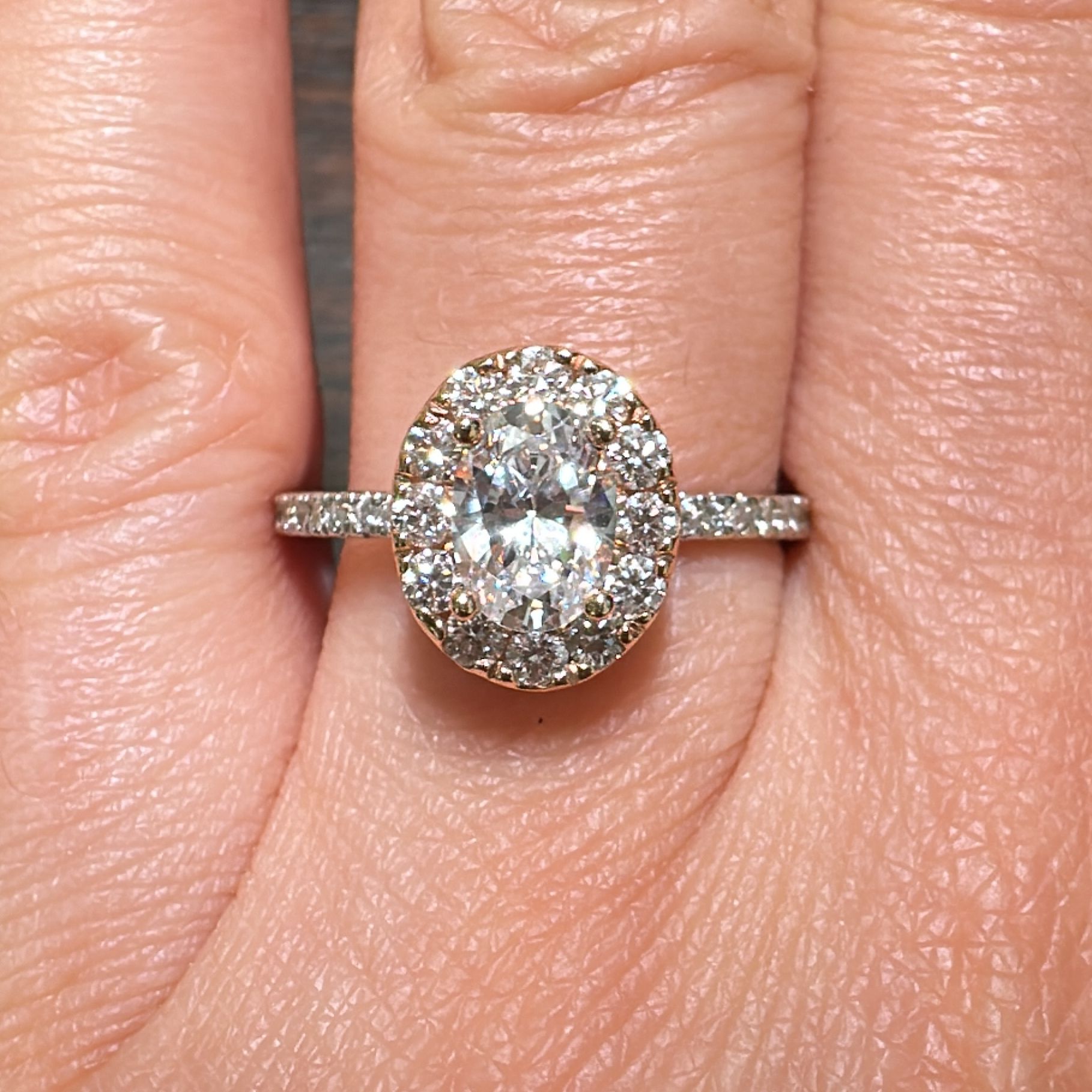 1 CT oval moissanite halo engagement ring in 14K gold with small diamonds.
