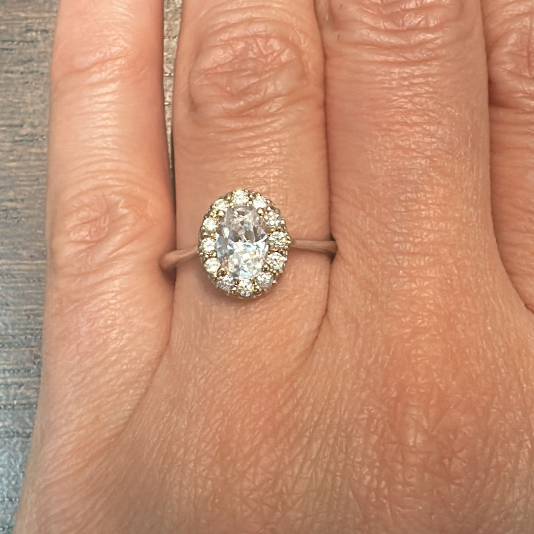 1 CT oval moissanite engagement ring with halo diamonds on 14K gold band.