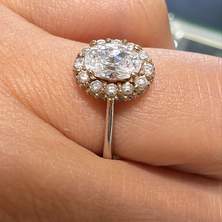 1 CT oval moissanite engagement ring with halo diamonds on 14K gold band.