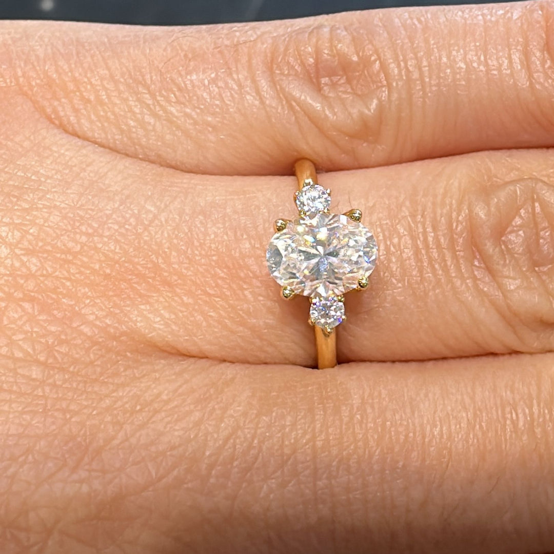 1.20 CT oval moissanite engagement ring with side stones on a 14K gold band.