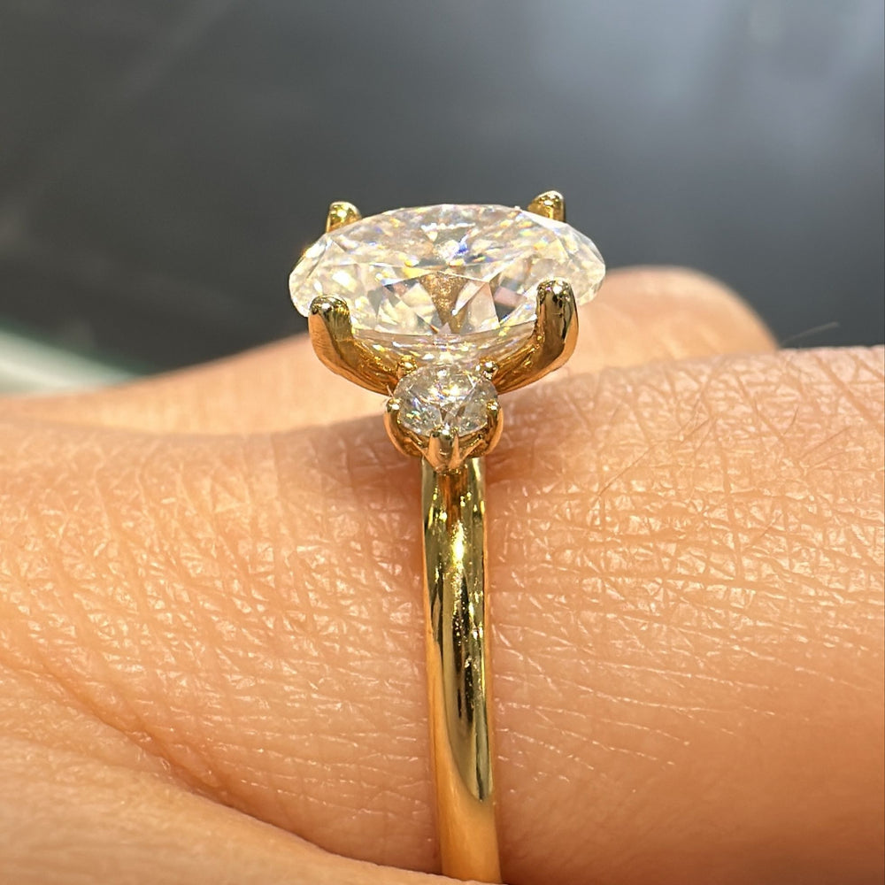 1.20 CT oval moissanite engagement ring with side stones on a 14K gold band.