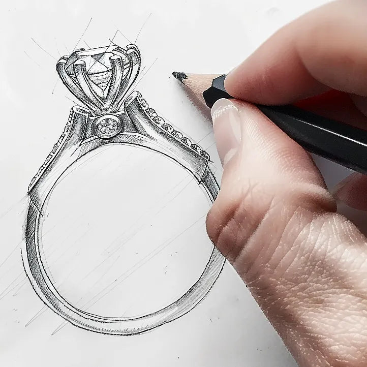 Hand sketching a detailed engagement ring design with a prominent center stone and decorative band, illustrating the custom design process